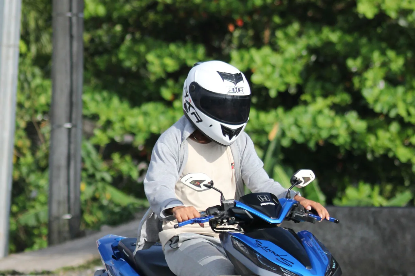 En fører med hjelm kører på en mindre scooter